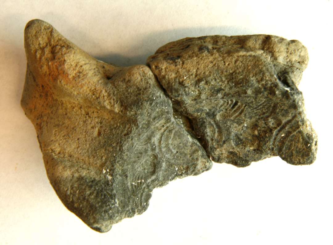 1 fragment af st�beformsoverdel af br�ndt ler til sk�lformet sp�nde med ornamentik p� indersiden. M�l : 3,5 x 3,4 cm. Tykkelse : 1,7 cm. Sammenlimet med D10585.