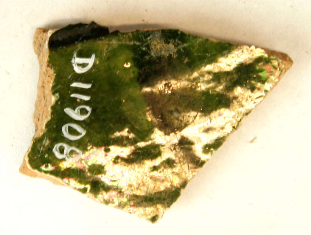 1 sidesk�r fra fad af r�dbr�ndt lergods med pibelersbegitning og uj�vn gr�nlig blyglasur p� ydersiden. Gr. 1.