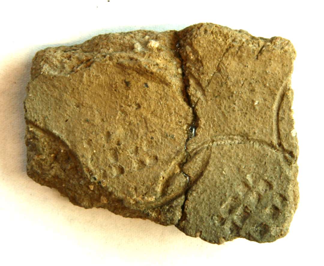 1 skuldersk�r. Ydersiden stempelornamenteret med kvadratisk gitterm�nster, omgivet af cirkelslag. Gr. 5. St. H: 3,8 cm. 2 sk�r sammenlimet.