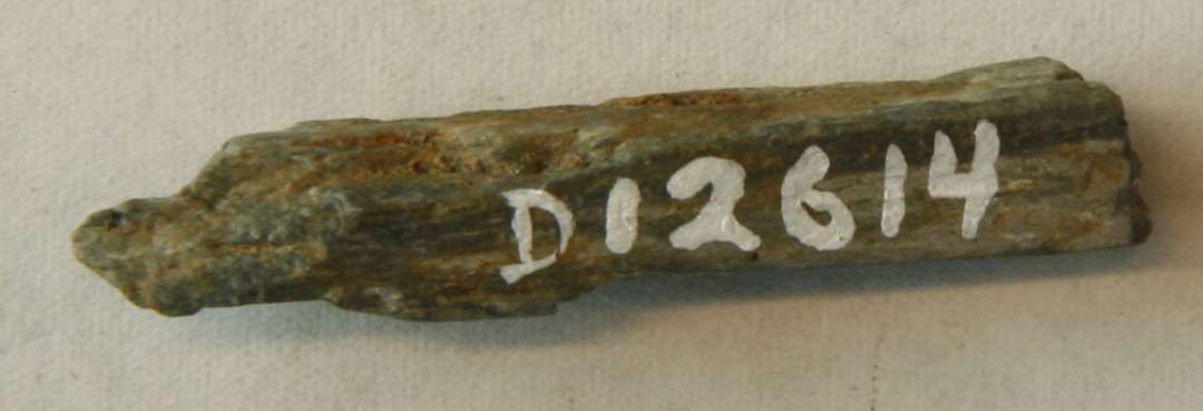 1 brudstykke af hv�ssesten af gr� skifer. Slidflade p� den ene side.�L: 4 cm.