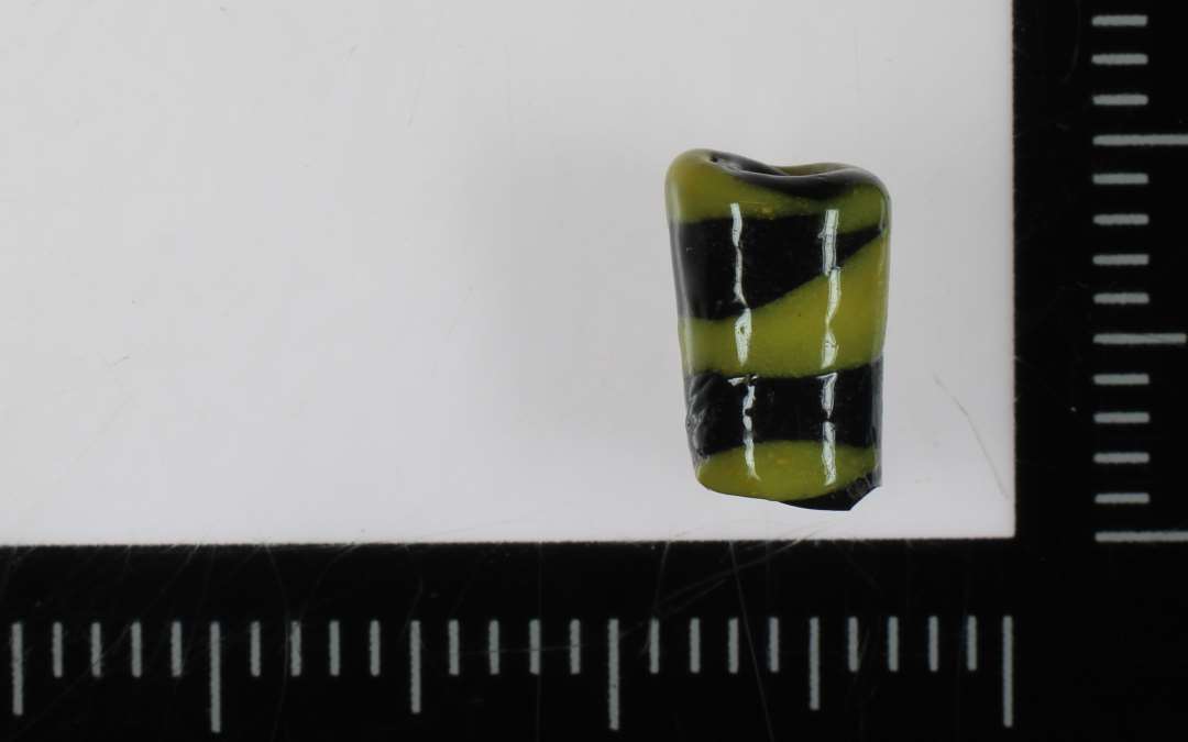 1 cylinderformet perle af spiralsnoet sort og gul ugennemsigtig glasmasse. 9 mm.