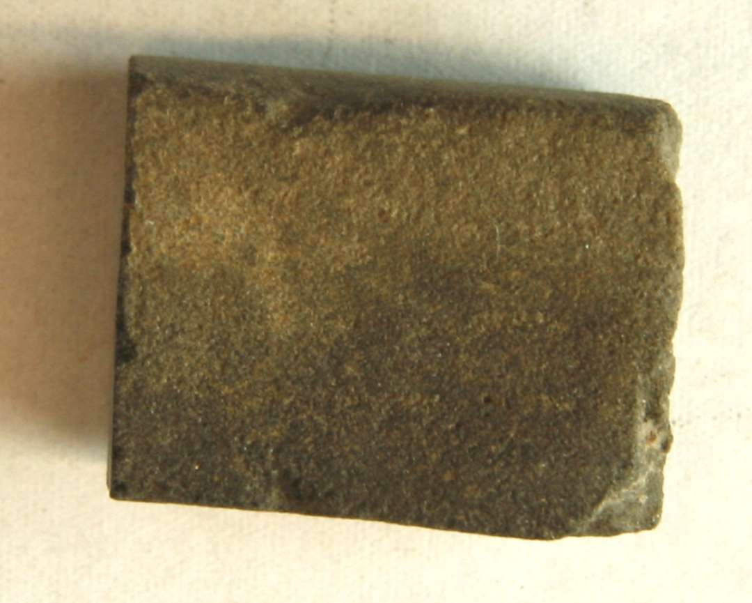 1 fragment af stangformet hv�ssesten af sandsten. Stykket har kvadratisk tv�rsnitsform og er overbrudt i begge ender.�L: 3,3 cm. Tv�rm�l: 1,7 x 1,9 cm.