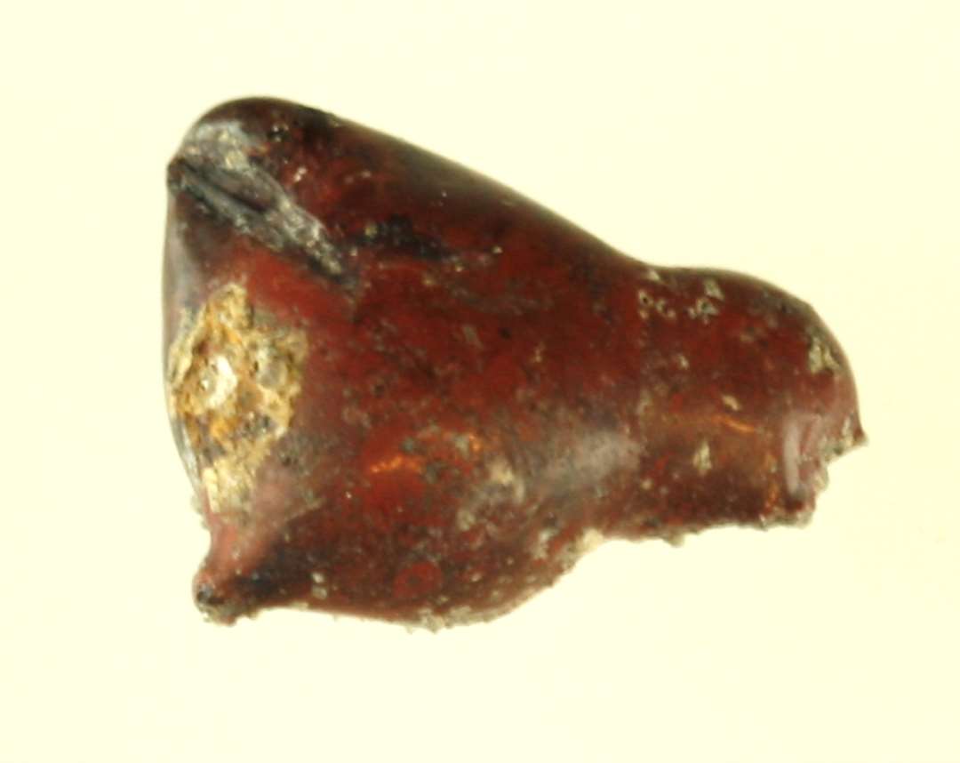 1 klump smeltet glas af �rteform og -st�rrelse af r�dbrunlig, ugennemsigtig masse.