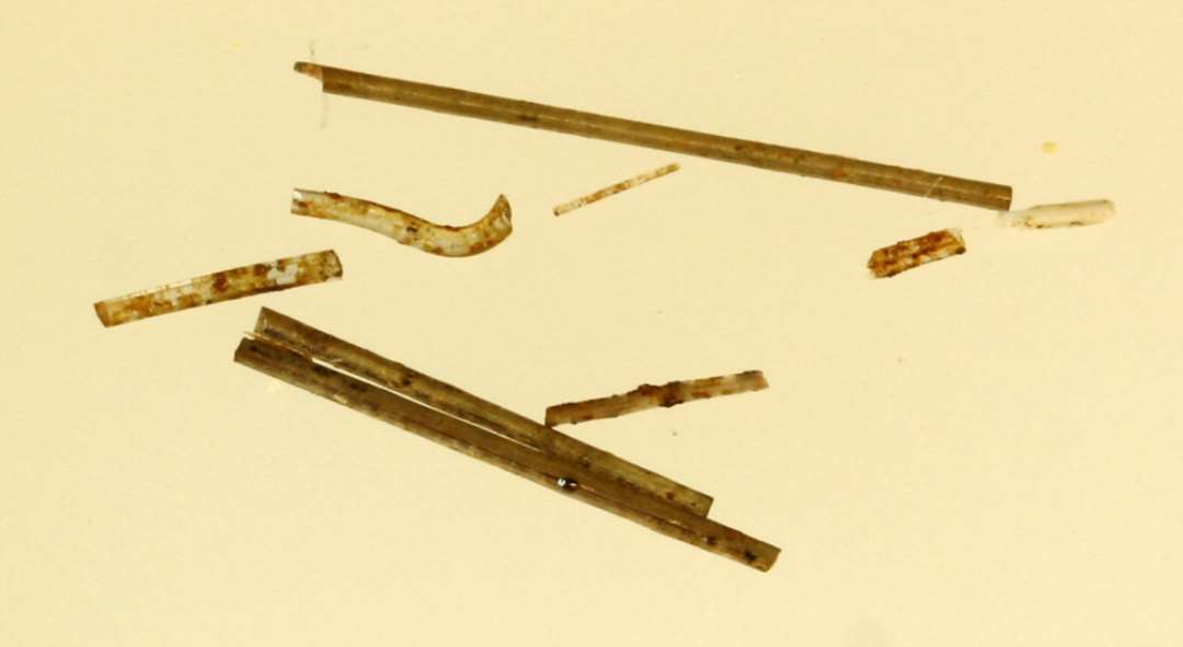 6 glastr�dsfragmenter af syn�lstykkelse af gennemsigtig glasmasse med fastkittet rust- og snavslag p� ydersiden.