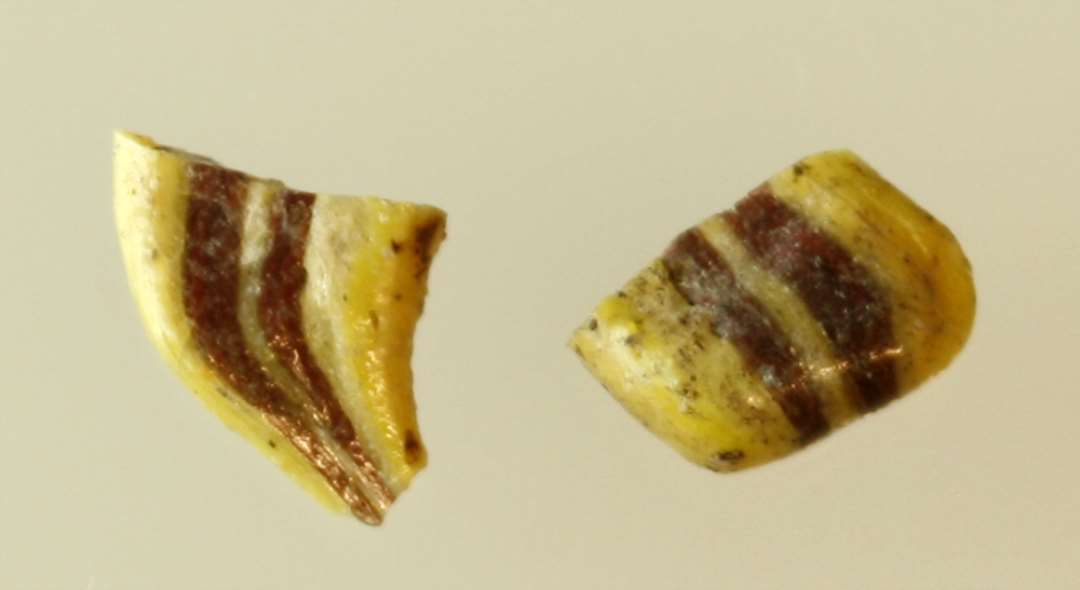 1 smeltet fragmentstump af bred stangform best�ende af gullig ugennemsigtig glasmasse med to indsmeltede tr�de af r�dbrunligt ugennemsigtigt glas. Sammenh�rende med D13428.�