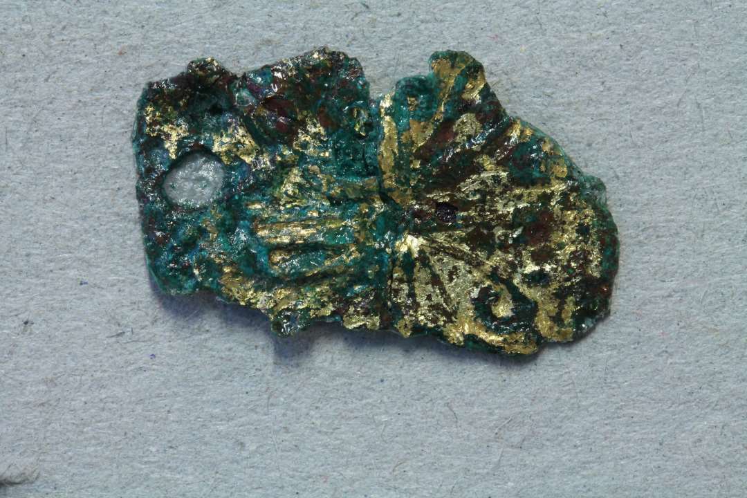 Fragment af bronzesmykke eller beslag. Forgyldt? Med blomsterornamentik. m�l: 2,2x1 cm