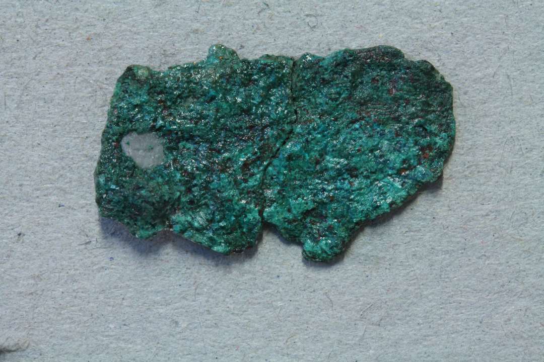 Fragment af bronzesmykke eller beslag. Forgyldt? Med blomsterornamentik. m�l: 2,2x1 cm