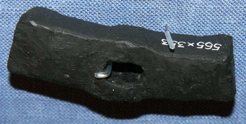 Et hammerhoved.�Midt p� hovedet et rektangul�rt skafthul.�L�ngde: ca.  6 cm.�Bredde:          2,0/1,5 cm.�Tykkelse: ca. 2 cm.