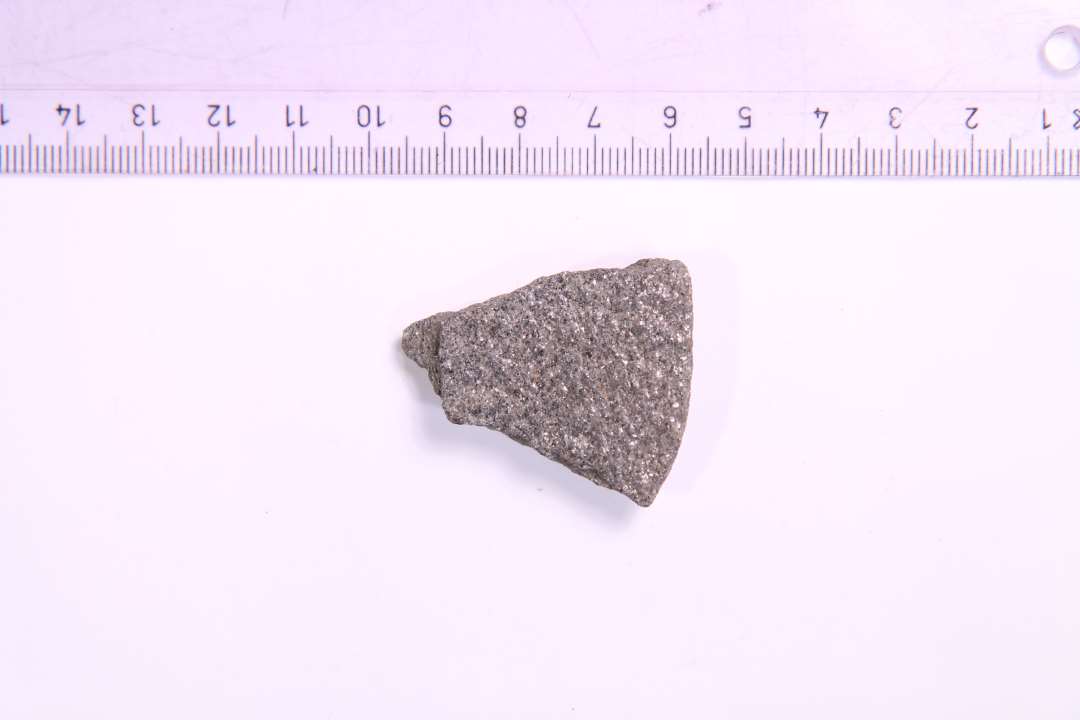 Fragment af glimmerskifer. Sandsynligvis af cirkul�r genstand med afrundet kant. Spillebrik? st�rste m�l: 4,2 cm.