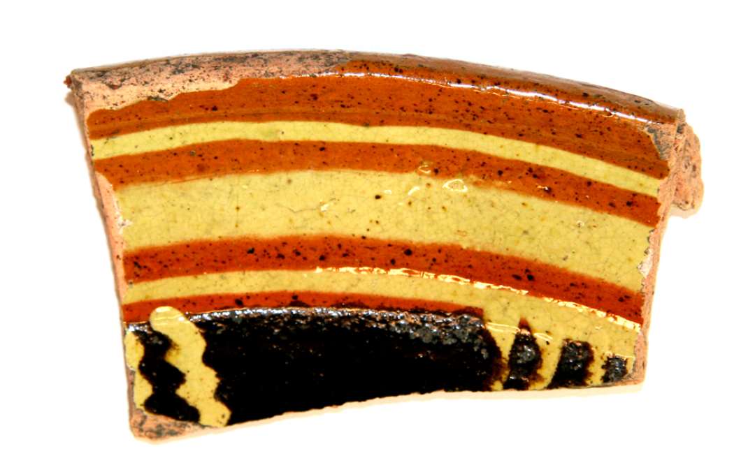 1 randsk�r fra hornmalet fad af r�dbr�ndt lergods med dekoration i pibeler og sortbrun mangan d�kket af klar blyglasur p� indersiden, gruppe 1.