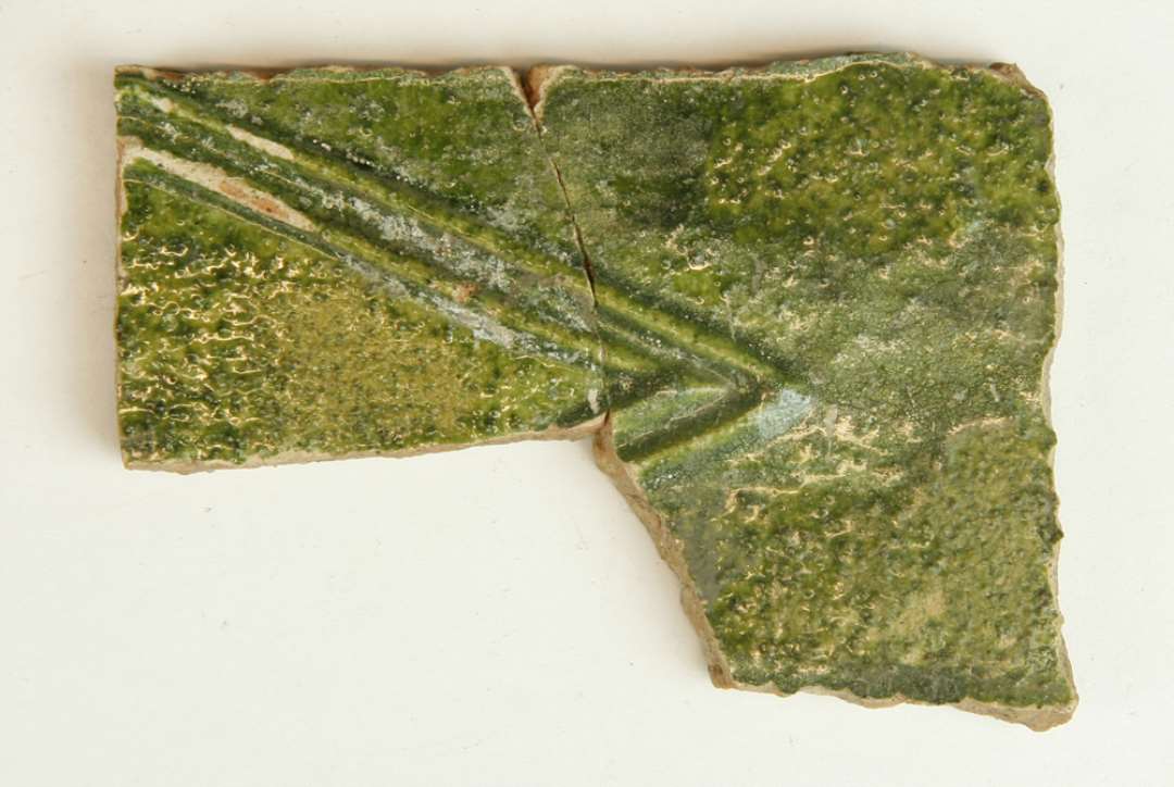 12 fragmenter af kakkelpotter og kakkelmidtfelter af r�dbr�ndt lergods med pibelersbegitning og gr�n blyglasur p� oversiden, 2 af fragmenterne fremviser udsnit af personer i ren�ssancetidsdragter. 1 stk. sammenlimet med D3178, 1 stk. sammenlimet med D6581.��