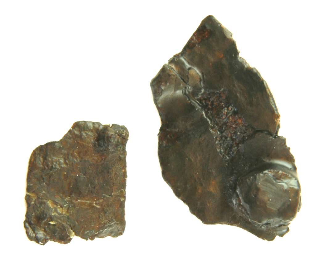 2 korroderede, flade jerngenstande begge med isiddende s�mstump. Ca. 1,5 x 2 cm. og 2,5 x 4,5 cm. Beslagafragment ?