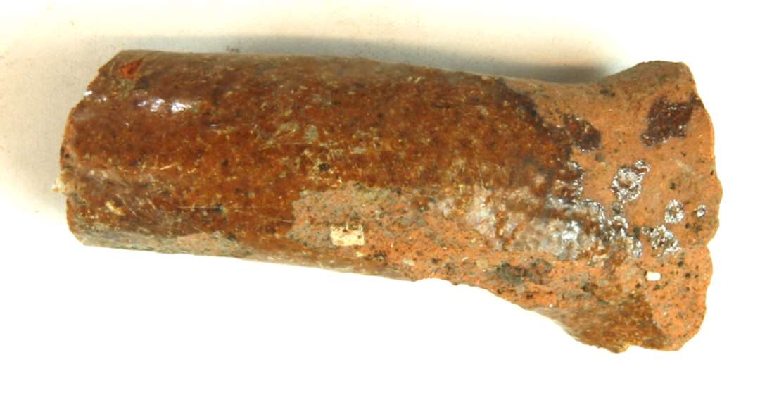 1 fragmenteret p�lseformet kandehank af r�dbr�ndt lergods med klar blyglasur p� oversiden.