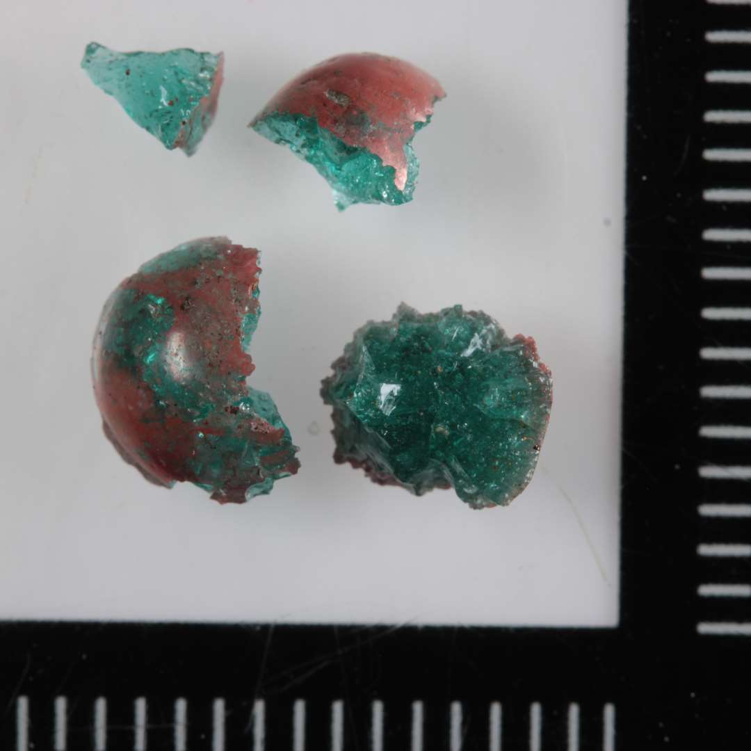 1 uregelm�ssig, kugleformig smeltet klump af gr�nlig glas med skinnende r�dbrunlig overflade.