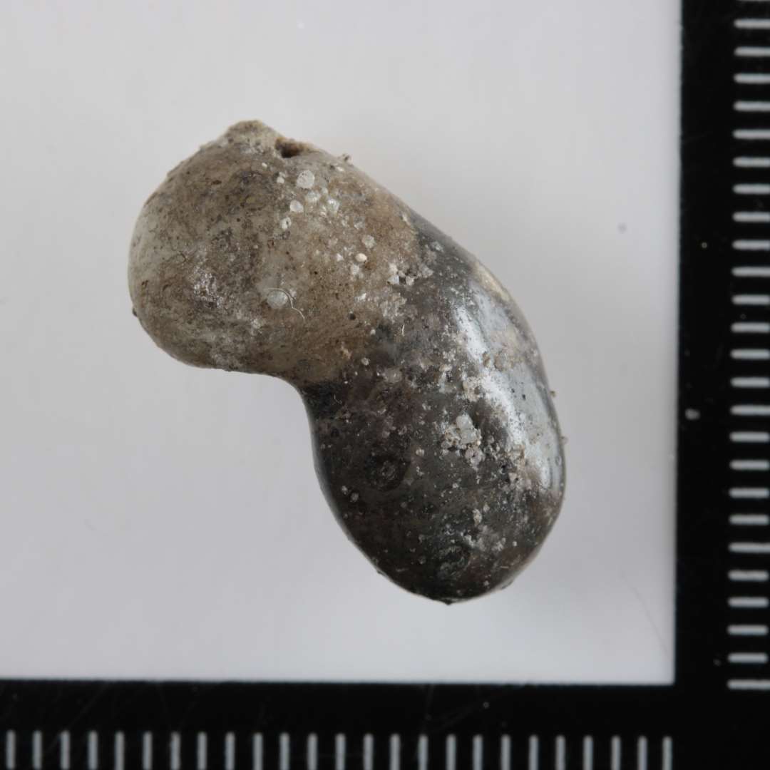 1 aflang, afrundet smeltet glasklump sammenklemt p� midten. Glasmassen er uigennemsigtig og den ene halvdel er hvidgr�, den anden m�rkegr�.