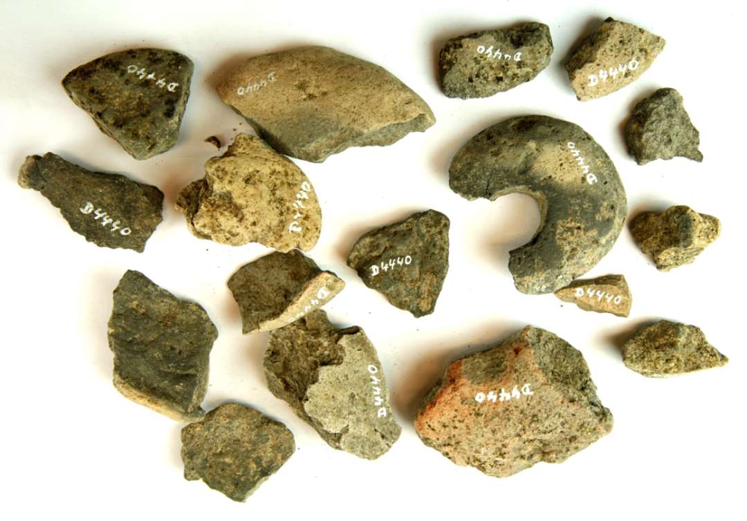 17 fragmenter af discosformede v�vev�gte af br�ndt lermasse. Et af fragmenterne udviser en r�kke t�t anbragte, dybt indprikkede, ganske sm� huller.