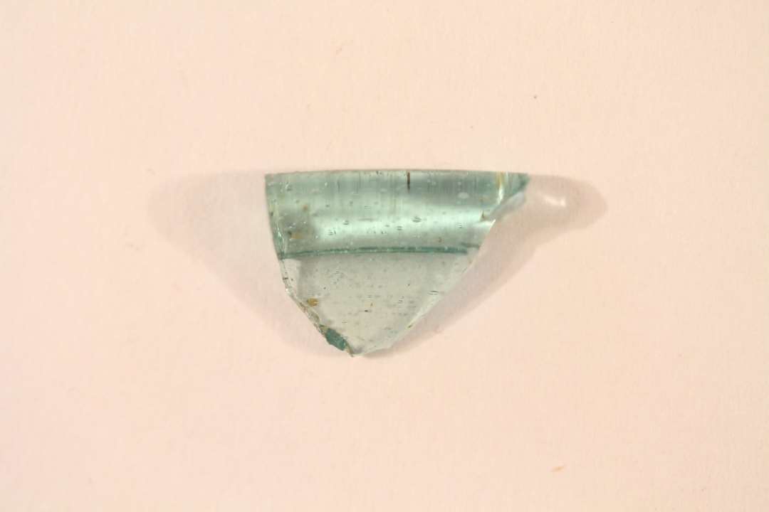 1 randsk�r med fortykket, vulstformet kant fra b�ger af svagt gr�nligt, gennemsigtigt glas med fine bl�rer.�St. m�l: 1,3 x 0,9 cm.�Tykkelse af randkant: 0,35 cm.