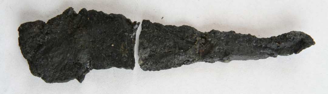 1 forrustet jerngenstand af flad aflang tresidet form.�L�ngde:  8,0 cm.�Bredde:    1,3 - 3,5 cm.�Tykkelse: 1,2 cm. Br�kket i to dele