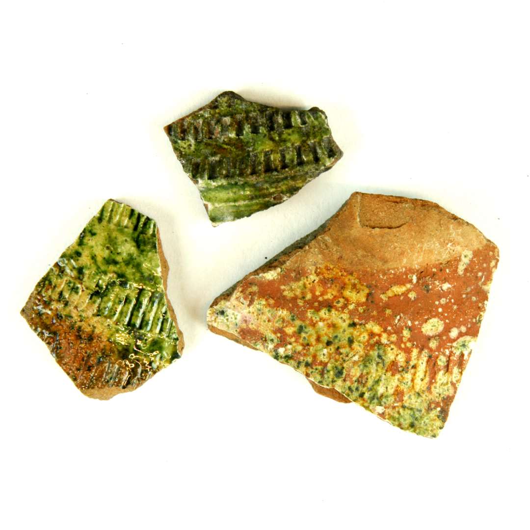 3 bugsk�r af r�dbr�ndt flamsk kande der p� ydersidn fremviser ornamenter af indstemplede t�tstillede skr� og lodrette streger af varierende l�ngde og tykkelse. Ydersiden er helt eller delvis d�kket af pibelersagtigt begitning hvorover gr�nligsp�ttet blyglasur.