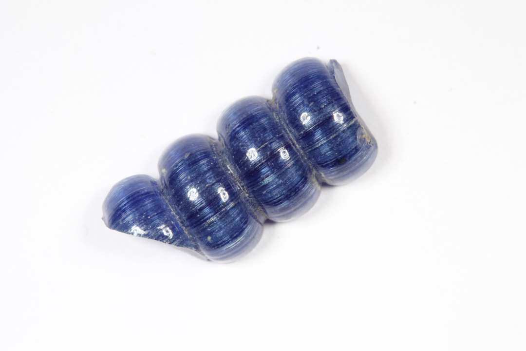 Halv segmenteret, halvgennemsigtig bl� glasperle. 4 segmenter. L�ngde: 1,7 cm.