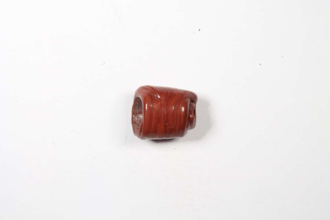 Cylindrisk, uigennemsigtig r�d glasperle. L�ngde: 0,8 cm.