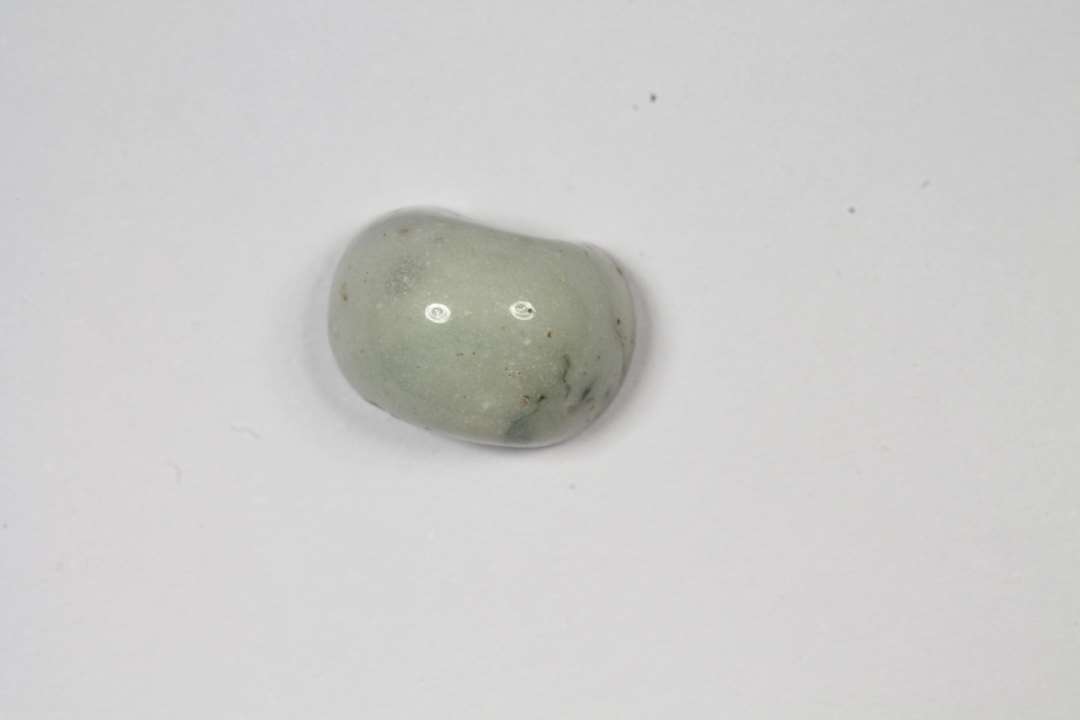 Halv ringformet, uigennemsigtig hvidgr� glasperle. Diameter: 1 cm.