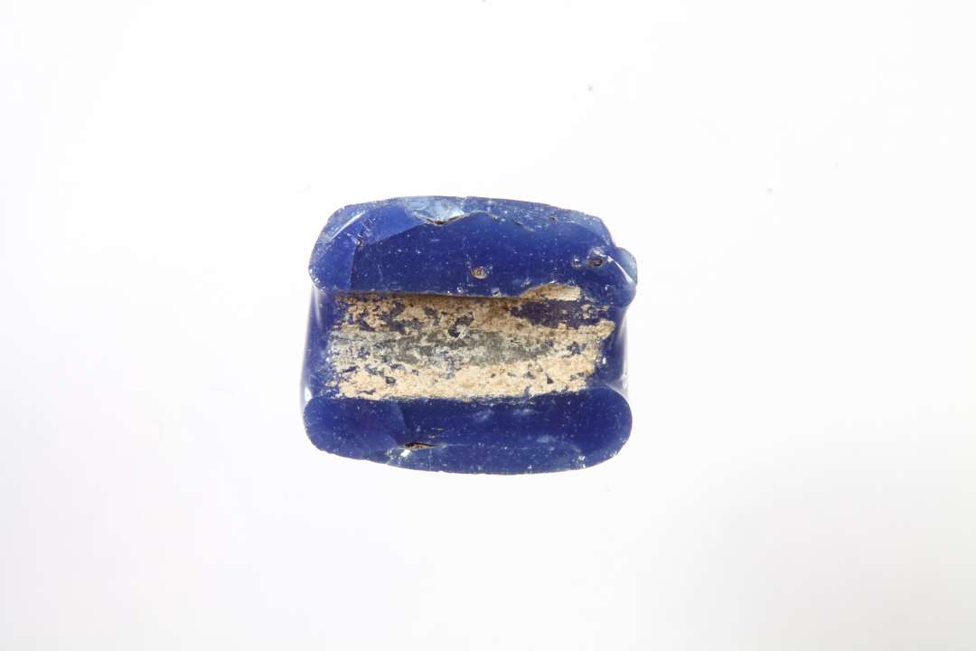 Halv bl� cylindrisk gennemsigtig glasperle. St�rste m�l: 1 cm.