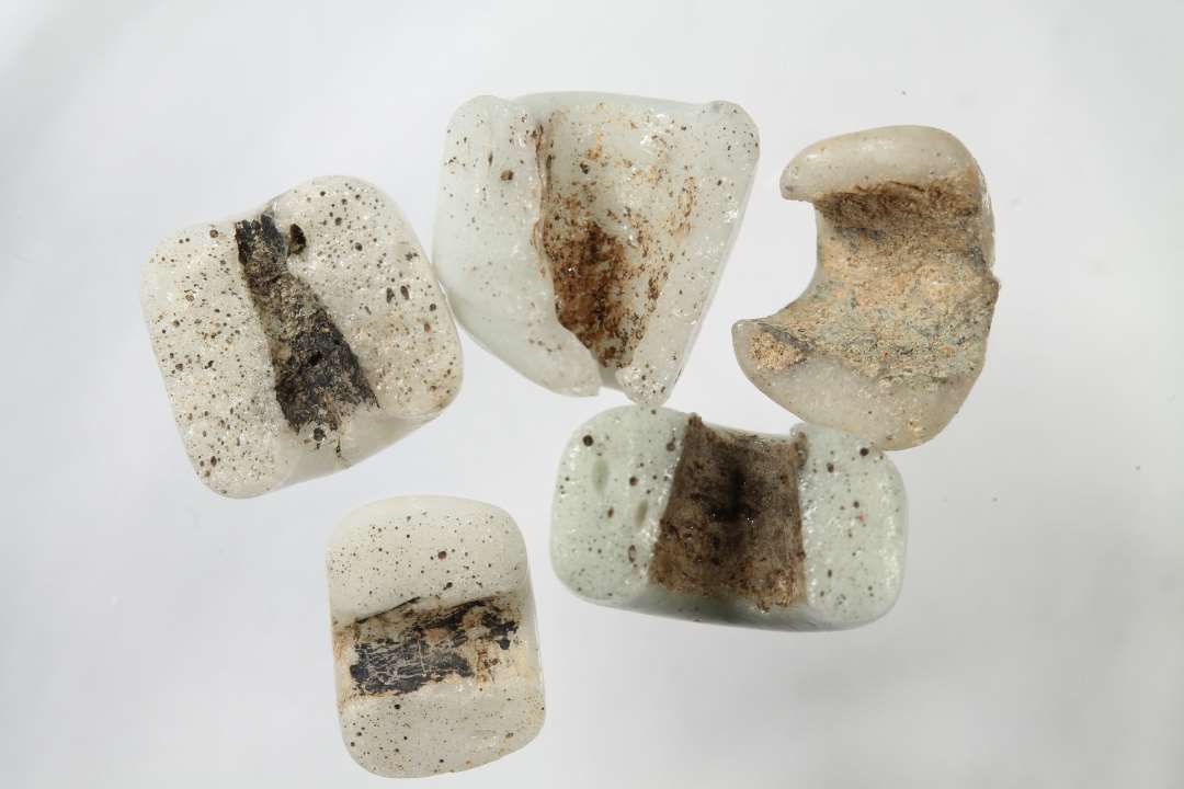 Fem halve cylindriske, uigennemsigtige, hvidgr� glasperler. Diameter: ca 0,7-1 cm.