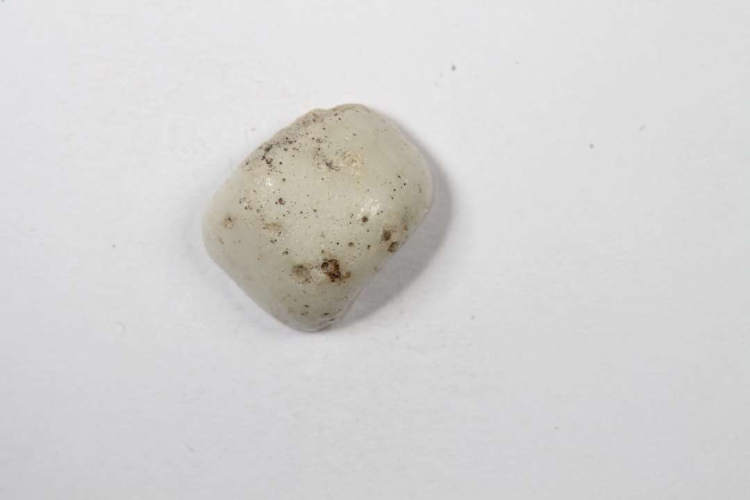 Halv cylindrisk, uigennemsigtig hvidgr� glasperle. Diameter: 1 cm.