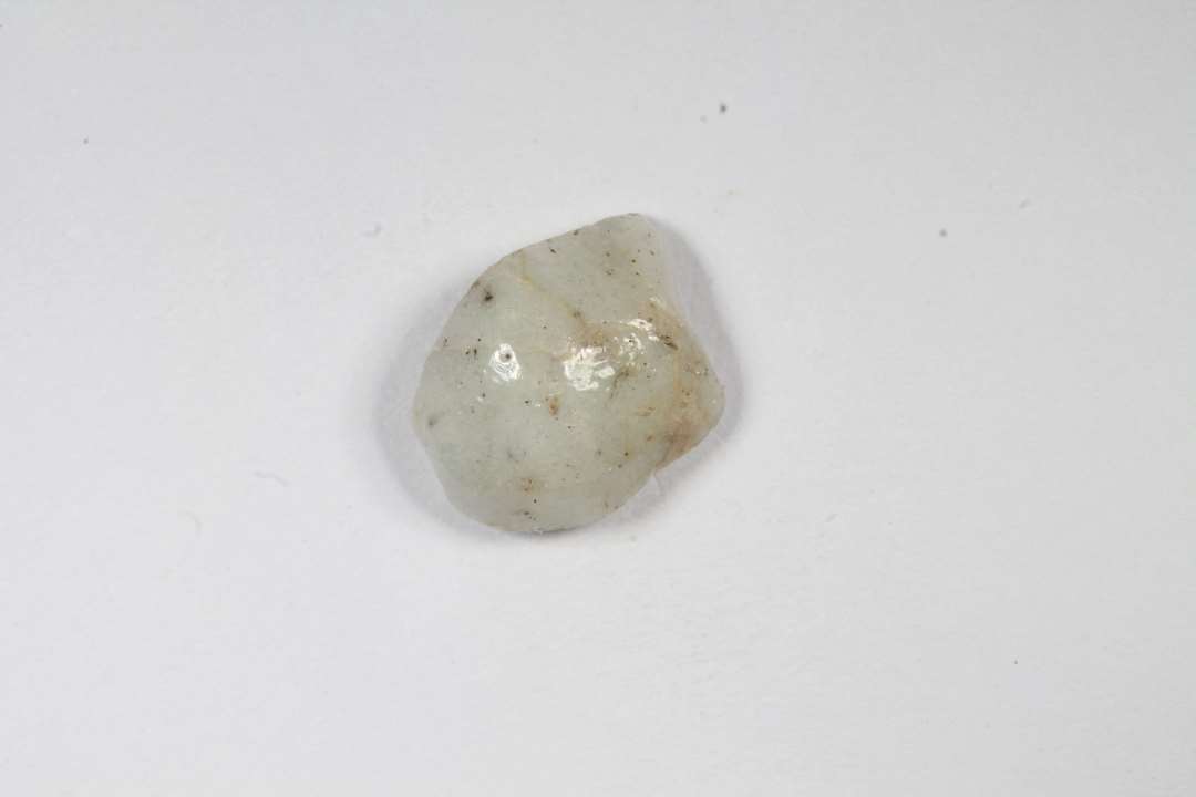 Fragment af dobbeltkonisk, uigennemsigtig, hvidgr� glasperle. St�rste m�l: 0,9 cm.