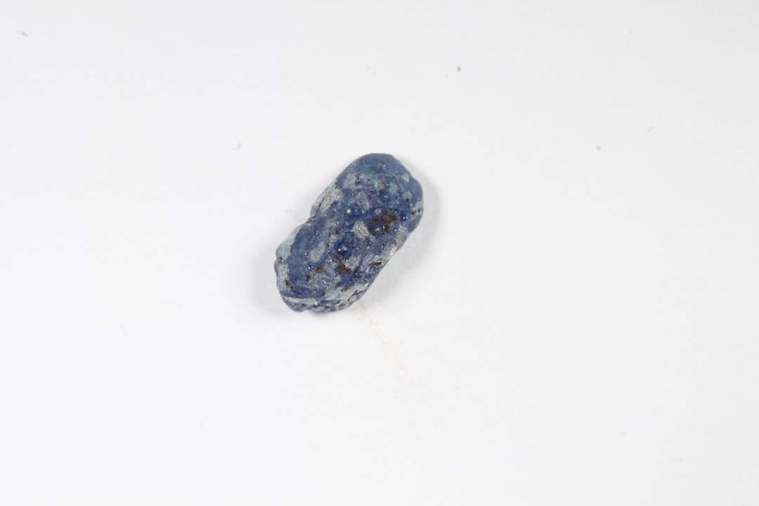 Fragment af ringformet, bl�, gennemsigtig glasperle med slidt overflade. St�rste m�l: 0,8 cm.