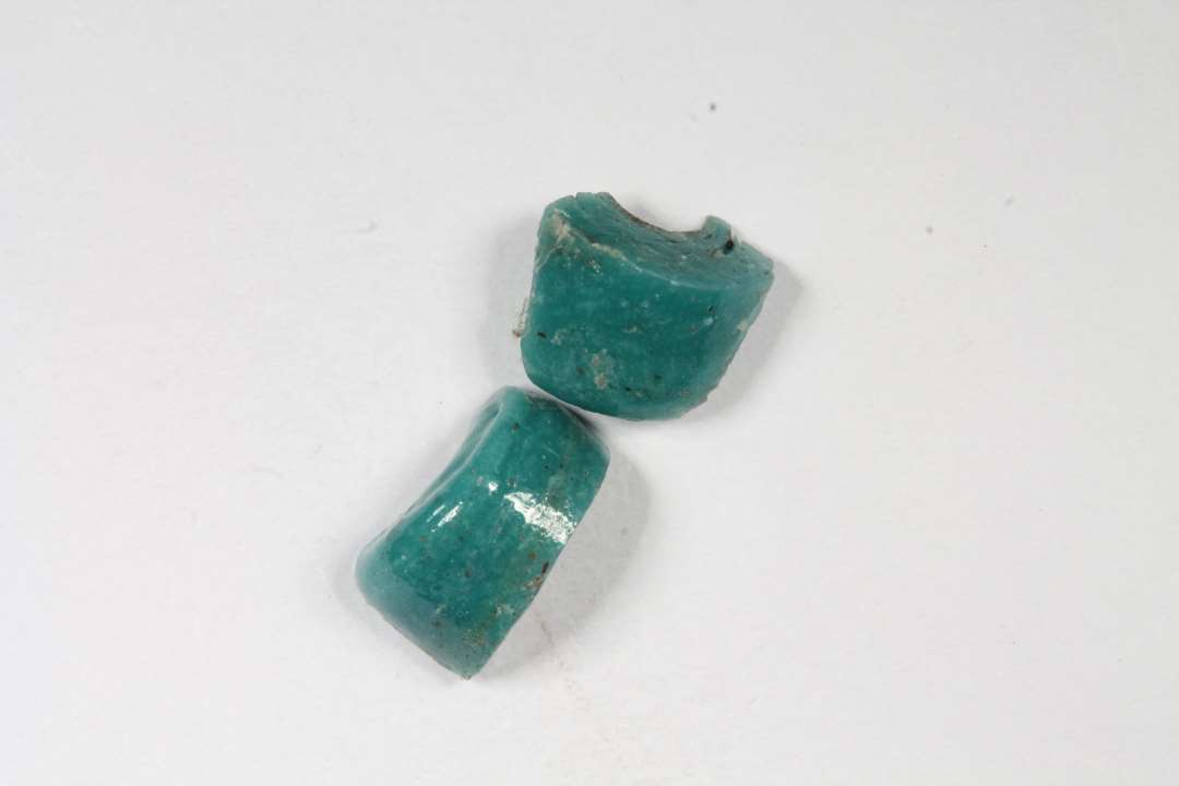 To fragmenter af cylindriske, uigennemsigtige gr�nne glasperler. St�rste m�l: 0,7 og 0,8 cm.