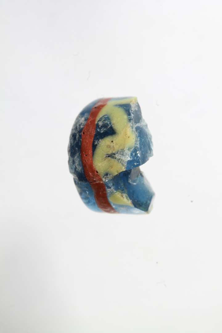 Tre fragmenter af cylindriske ribeperler, gennemsigtig bl� med r�dt og gult. To af fragmenterne er sammenh�rende/sammenlimet