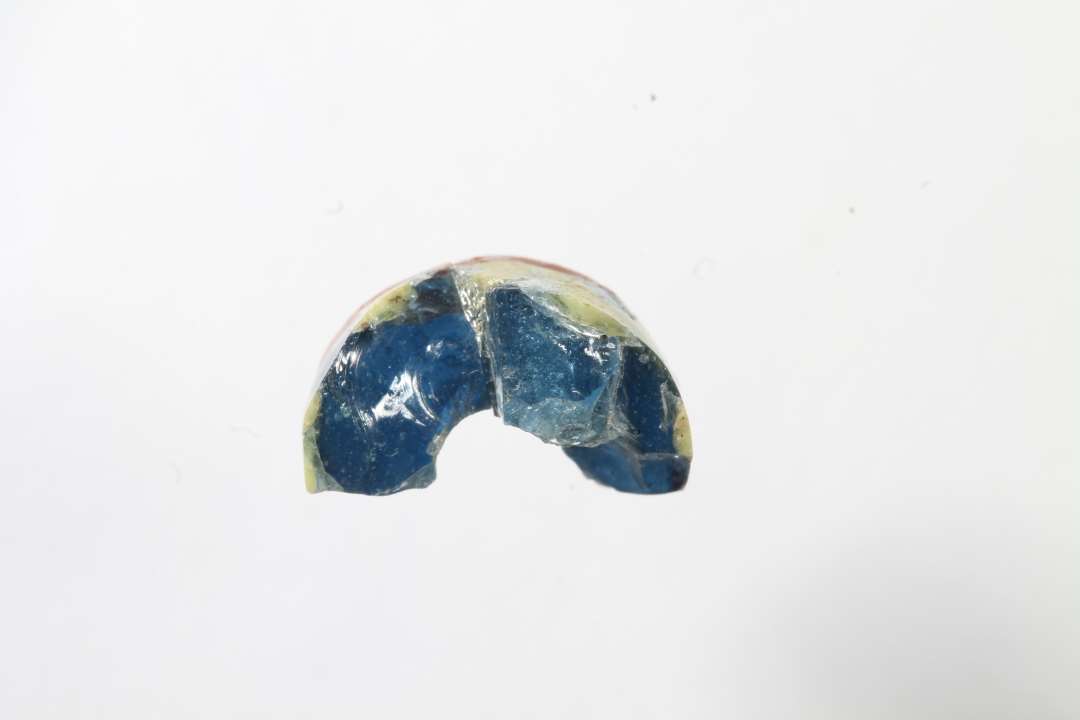 Tre fragmenter af cylindriske ribeperler, gennemsigtig bl� med r�dt og gult. To af fragmenterne er sammenh�rende/sammenlimet