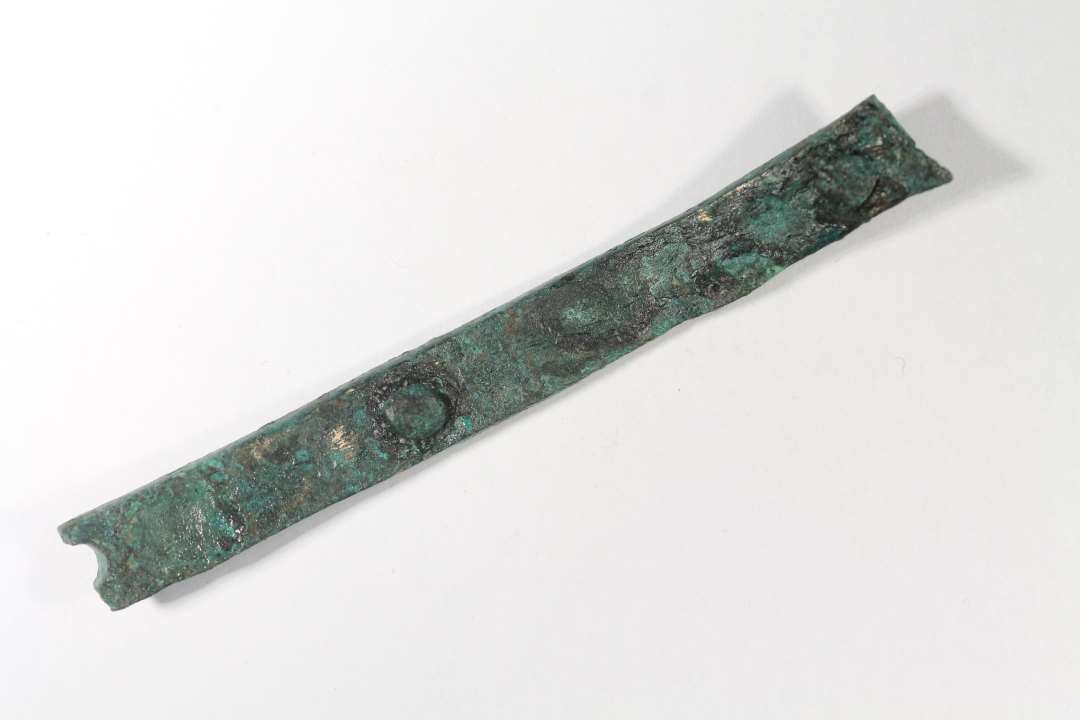 Bronzestang. Krum, med to bronzenitter, samt det halve hul efter endnu en. Afbrudt i�begge ender. M�l: 8 x 0,9 x 0,3 cm.