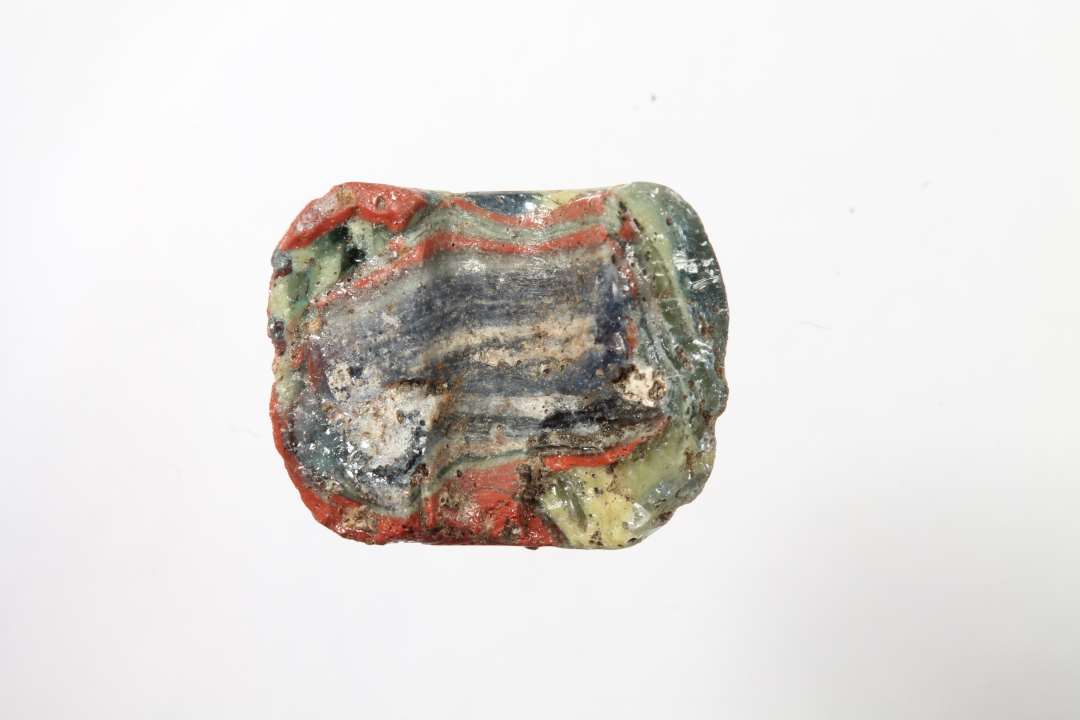 Halv t�ndeformet mosaikperle, halvgennemsigtig, bl� med r�dt, gult og hvidt. Diameter: 1,2 cm.