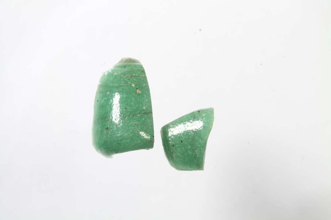 To fragmenter af cylindriske, uigennemsigtige, gr�nne glasperler