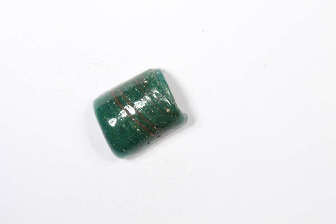 Tre halve cylindriske, uigennemsigtige gr�nne glasperler. L�ngde: 0,8 cm.