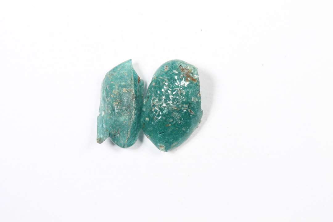 To fragmenter af cylindriske, uigennemsigtige turkise glasperler