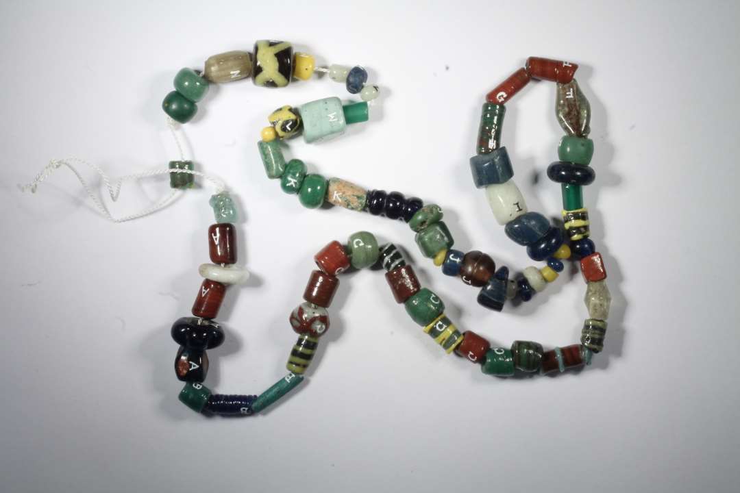 Tre hele cylindriske, uigennemsigtige gr�nne glasperler, den ene med lidt r�dt glas, den anden med en del r�dt glas iblandet