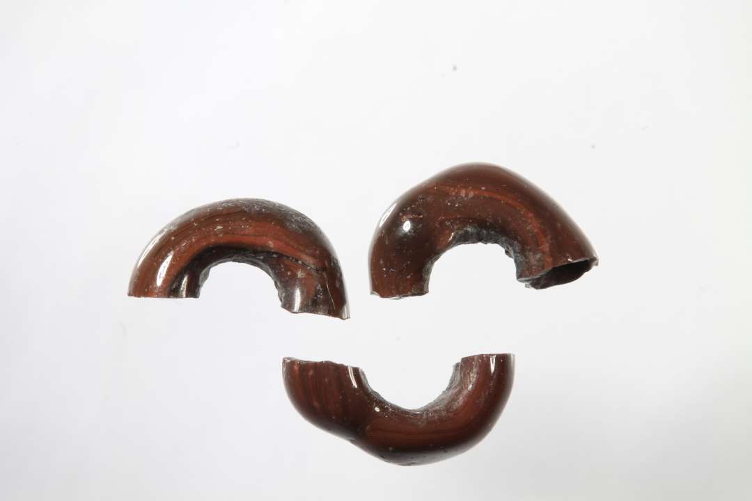 Tre halve ringformede, uigennemsigtige, r�dbrune glasperler