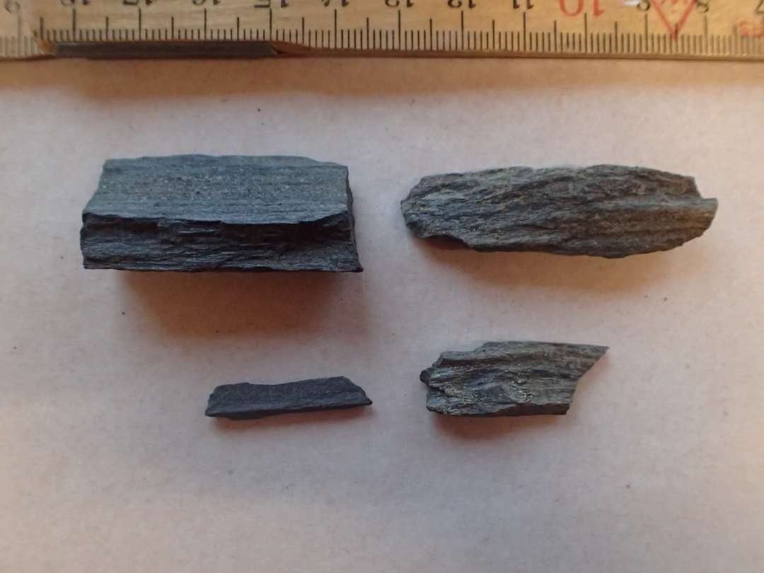 4 fragmenter af hv�ssesten af m�rkegr� skifer. Uden slibeflader. M�l: 2,6-5 cm.