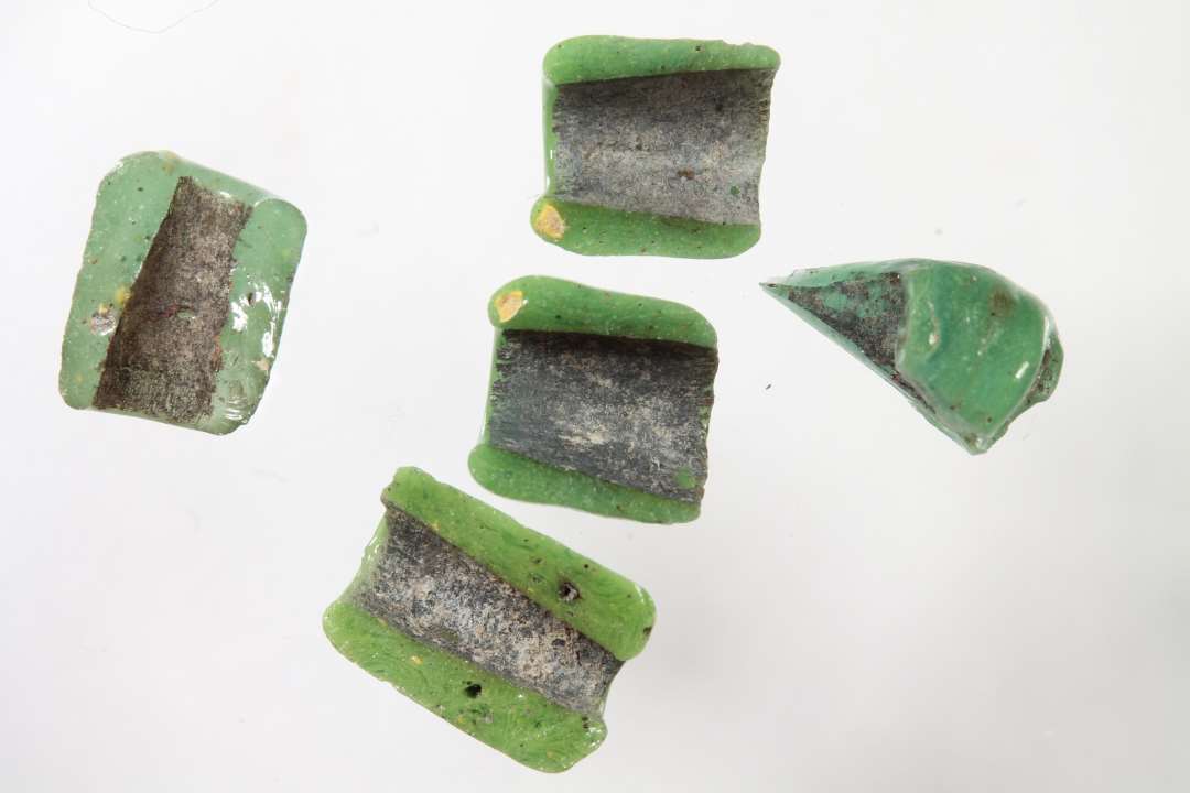 Fem halve cylindriske, uigennemsigtige, gr�nne glasperler. En med lidt r�dt, 1 med lidt gult iblandet