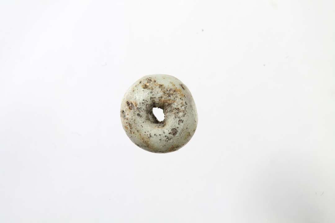 Ringformet, uigennemsigtig, hvidgr� glasperle. Diameter: 0,8 cm.