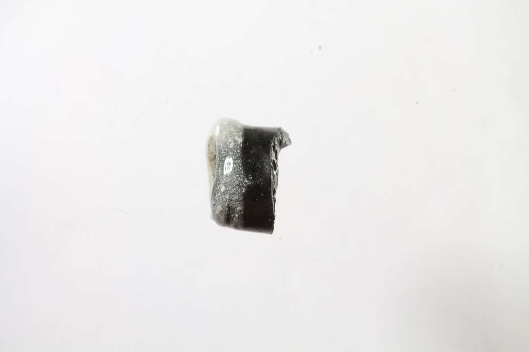 Fragment af cylindrisk hvepseperle, Uigennemsigtig. Sort med hvidt b�nd. Diameter: 0,7 cm.