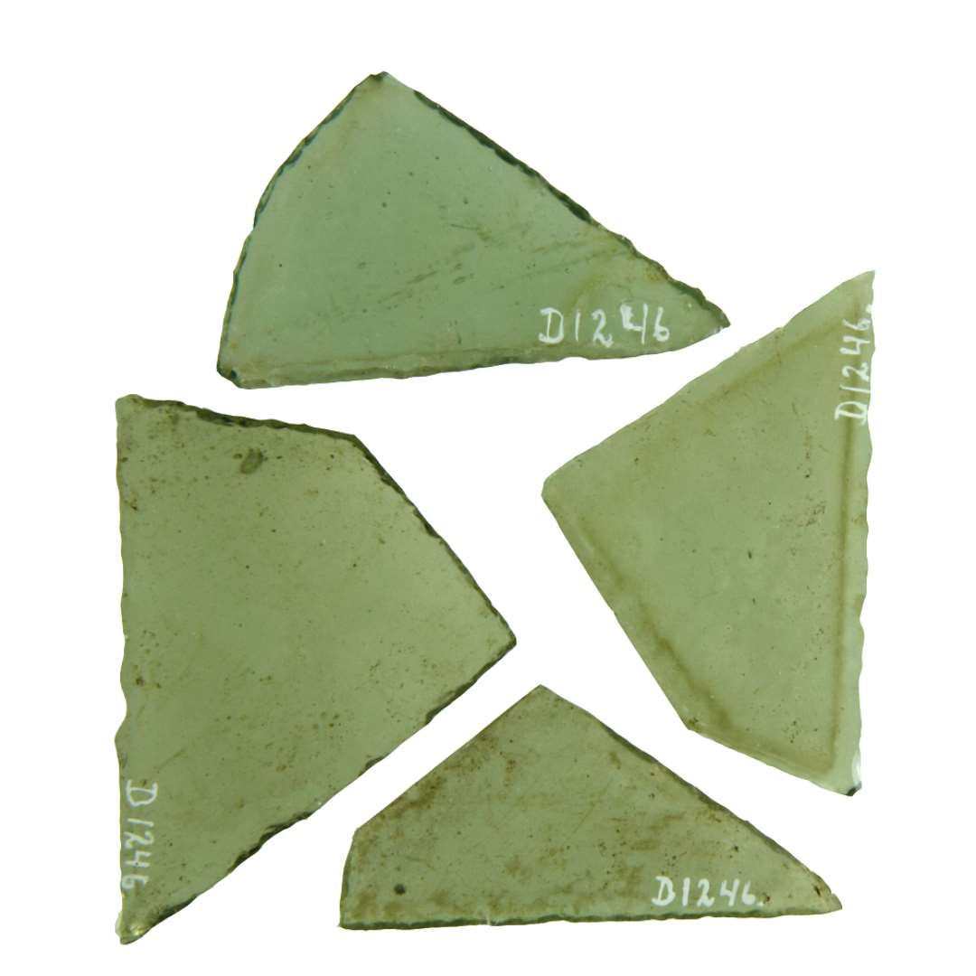 4 hele ruder af klart, gr�nligt glas af form som sk�v, spidsvinklet trekant med det ene spidse hj�rne skr�t afsk�ret, s�ledes at her opst�r et stumpvinklet kn�k p� den ene trekantside. 2 af ruderne har afnappede kanter, 2 har dels afnappede kanter. Rudernes st�rste l�ngde: 6,05 - 6,25 - 6,4 - 6,6 cm. Deres st�rste h�jde: 2,9 - 3,8 - 4,2 - 4,9 cm.