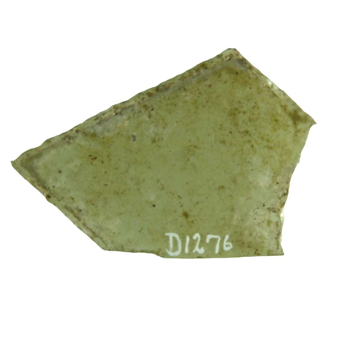 1 rudefragment af klart gr�nligt glas med afnappede kanter. Ruden har antagelig haft form af en rhome med afsk�ret spids idet den afsk�rende linie har svag konkav form. Den ene side med de 2 stumpe hj�rner afbrudt. St�rste m�l: ca. 5 x 7,2 cm.