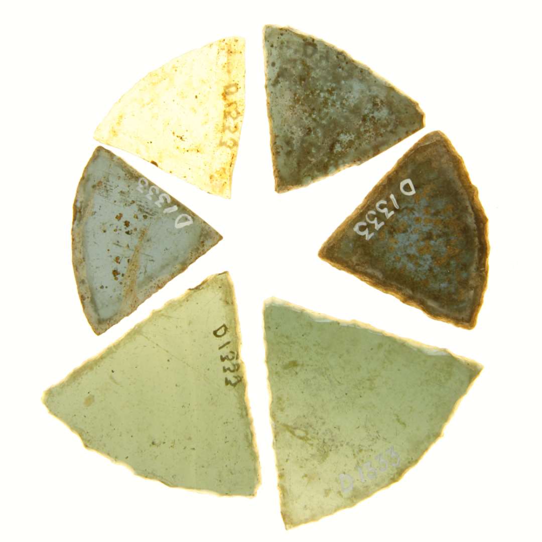 6 hele ruder af bl�t glas med delvis afnappede kanter af form som cirkeludsnit med en centrumsvinkel p� 65 grader.  Rudernes st�rste m�l: 3,8 x 3,15 cm. - 3,95 x 3,25 cm. - 4,0 x 3,2 cm. - 4,15 x 3,55 cm. 5,0 x 4,7 cm. - 5,3 x 4,6 cm. 