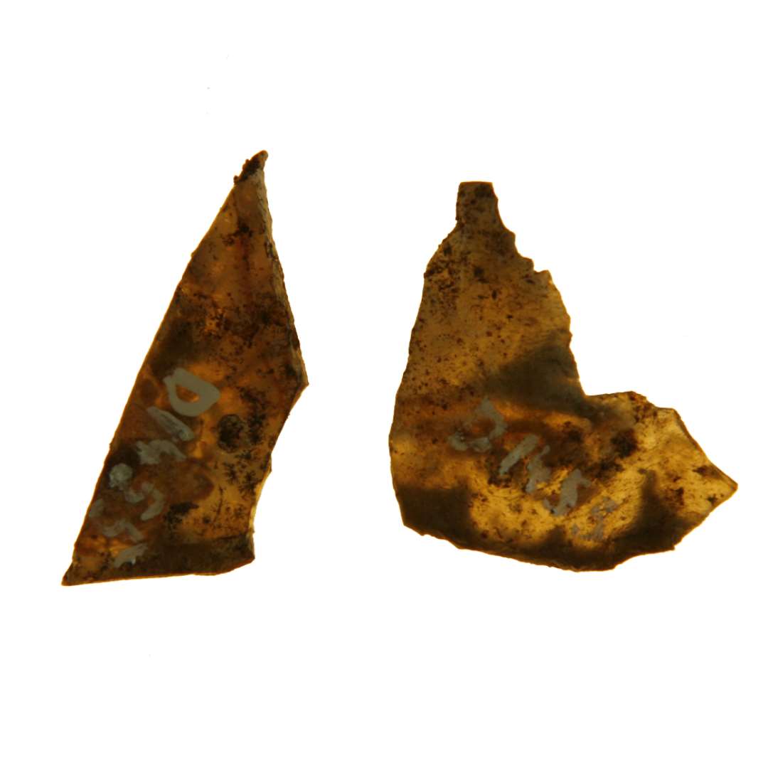 2 fragmenter af ruder af klart gr�nligt glas med spor af afnappede kanter. Begge fragmenter er mere eller mindre forvredne p� grund af smeltning og er forsynet med plantemotivsdekoration i st�rk stiliseret form i henholdsvis brun og r�dlig farve. St�rste m�l: 1,35 x 3,8 cm. - 2,2 x 3,25 cm.