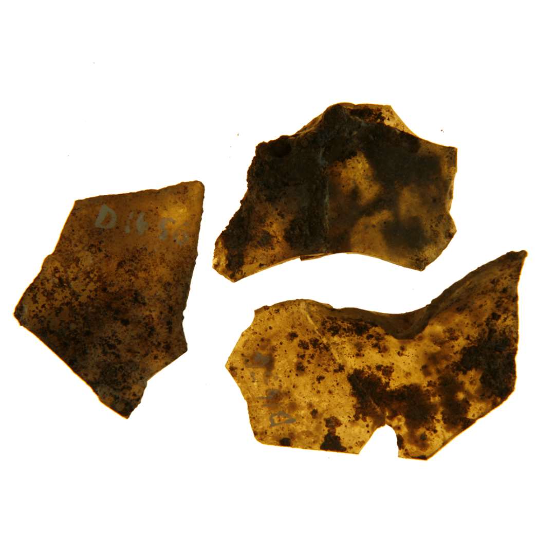 13 fragmenter af ruder eller rudeglas alle af klart, gr�nligt glas. Fragmenterne viser spor af flere af kanterne undertiden ogs� spor af tangnapning ( i ophedet stand). Alle fragmenterne b�rer mere eller mindre pr�g af sammensmeltning, hvorved bestemmelse af rudeformen vanskeligg�res. St�rste m�l: 2,3-5,4 cm.